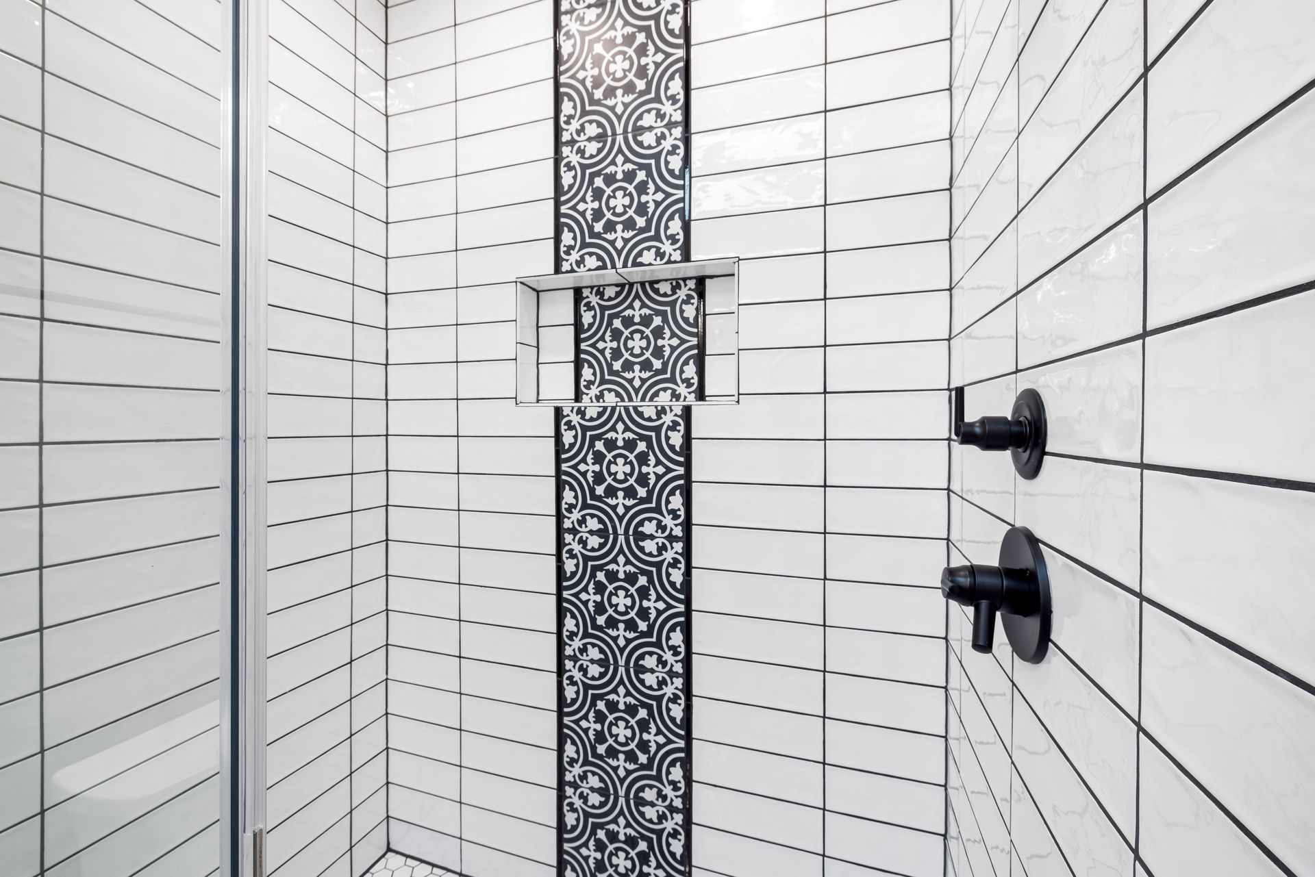 Stylish shower area featuring black and white geometric tiles and contemporary fixtures.